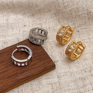 Detailed view of silver and gold pavé-set zircon hoop earrings on a rustic linen background