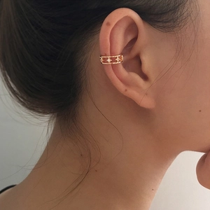 Detail of gold star-shaped ear cuff with sparkling zircon stones on female ear