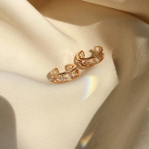 Gold double-layered star ear cuff with sparkling zircons on soft beige satin fabric