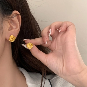 Close-up of elegant gold camellia flower earrings with detailed multilayered petals