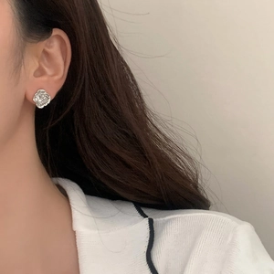 Detailed close-up of a vintage silver camellia stud earring worn on a female ear