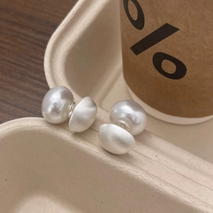 Detail view of double pearl stud earrings with matte and glossy finish on a tray