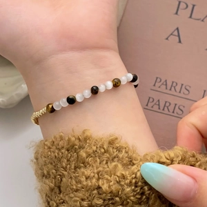 Detail of beaded tiger eye bracelet with translucent white beads and gold metal accents
