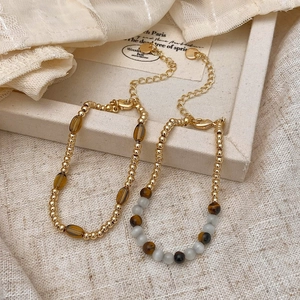Retro tiger eye beaded bracelets with gold accents and vintage charms on lace background
