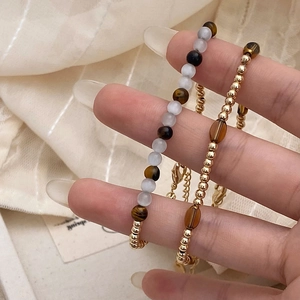 Detail of beaded bracelet set with tiger eye stones and gold metallic beads worn on wrist