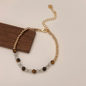 Detailed view of tiger eye beads and metal gold accents on an adjustable bracelet
