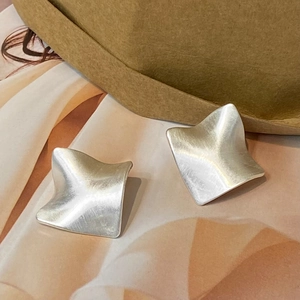 Macro view of vintage silver earrings featuring a minimalist brushed metallic texture