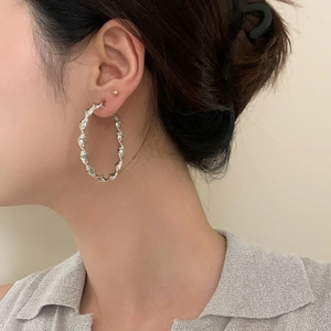 Macro detail of silver twisted hoop earrings featuring a stylish spiral metal texture