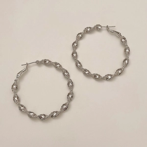 Detail view of silver twisted rope hoop earrings with glossy metallic mirror finish