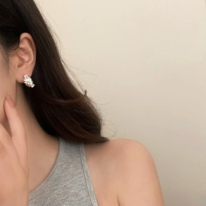 Detail of silver knot stud earring worn by a model, showing modern metallic texture