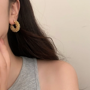 Close-up of gold beaded hoop earrings on model showing retro texture and French style