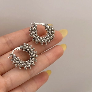 Close-up of silver hoop earrings featuring a unique beaded texture and metallic luster