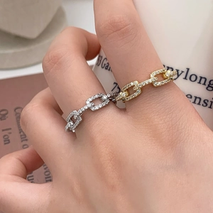 Close-up of minimalist chain-link rings with sparkling zircon pave in gold and silver
