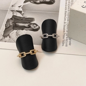 Minimalist gold and silver chain link rings with pavé stones on a black jewelry stand
