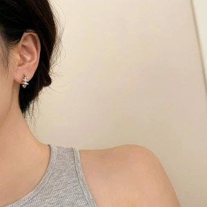 Close-up of silver spiral earrings with zircon inlay worn by a model in soft lighting