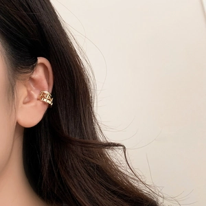 Detail of layered gold ear cuff with hollow geometric design and sparkling micro-diamonds