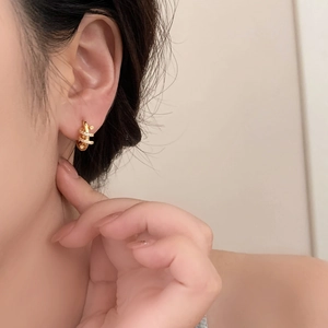Macro detail of gold-plated crossover hoop earrings with micro-set cubic zirconia stones