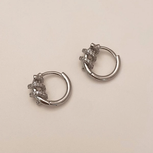 Detail of silver huggie hoop earrings featuring intertwined bands and micro-pave cubic zirconia