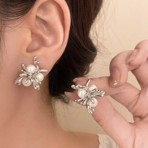 Detailed close-up of elegant silver firework earrings with white pearls on ear