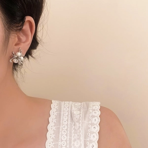 Detailed view of spider-shaped silver stud earrings with elegant pearls on ear