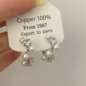 Close-up of French-style pearl and zircon hoop earrings on white display card