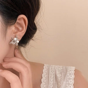 Elegant silver metal firework pearl stud earrings shown on a model's ear