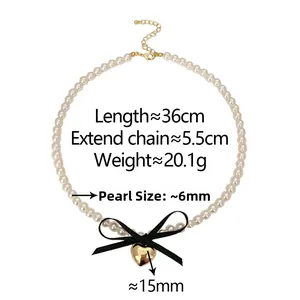 Detailed specs of double pearl necklace with black silk bow and gold heart pendant