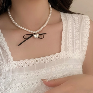 Double-layered pearl heart necklace with a black bow pendant for a French vintage look