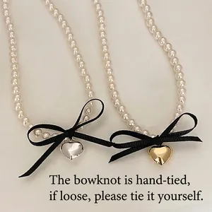 Double-layered pearl necklace with a black ribbon bow and a heart-shaped metal pendant