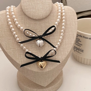 Double-layer pearl necklace with black ribbon bow and metallic heart pendant for women