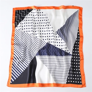 Detailed view of geometric silk scarf featuring navy polka dots and bright orange edges