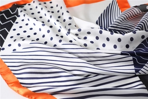 Detail of silk-like scarf featuring geometric polka dot patterns and orange contrast borders