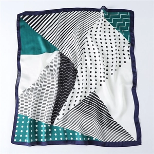 Detailed view of square silk scarf with geometric dot patterns and satin texture