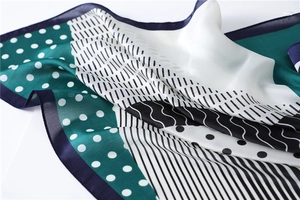 Detail of silk-satin scarf featuring polka dots and geometric patterns in deep green