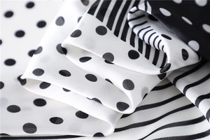 Detailed shot showing the silky texture of the black and white polka dot and striped scarf