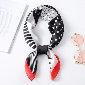 Chic silk-like scarf with polka dots and stripes next to sunglasses and a book