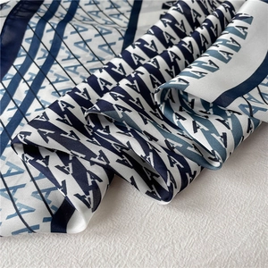 Macro shot of silk-like square scarf featuring geometric letter A patterns and striped edges