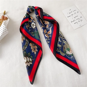 Close-up of floral silk scarf with red contrast borders on a minimalist white surface
