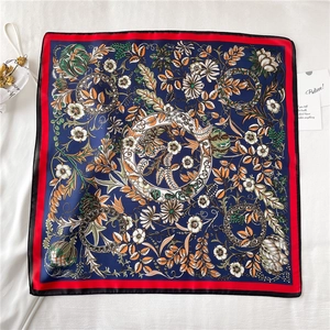 Detail of navy silk square scarf with red edges and intricate floral patterns