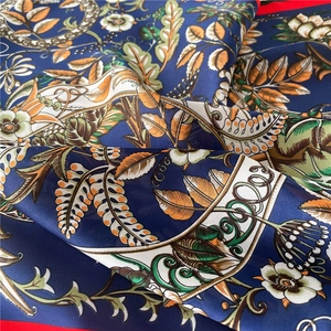 Detail of luxury silk square scarf featuring classic floral patterns and red borders