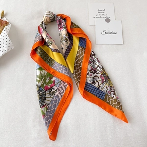 Detailed flat lay of vibrant floral silk scarf with orange borders and patterned design