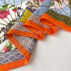 Detail of silk-like floral square scarf with bright orange rolled edge and soft drape