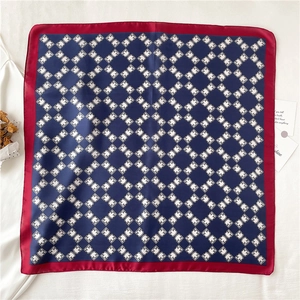 Close-up of navy blue silk square scarf featuring geometric patterns and red border