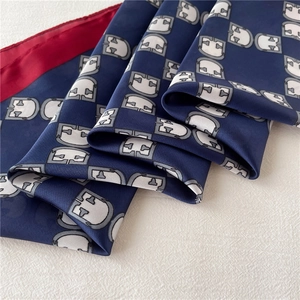 Close-up of navy silk scarf featuring burgundy edges and grey geometric patterns