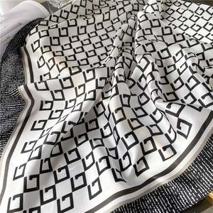 Detail of silk square scarf featuring black geometric G patterns on cream fabric