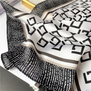 Detail of silk-like square scarf featuring geometric black and white patterns and soft folds