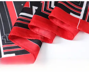 Detailed close-up of fine stitching and rolled edges on a red and black satin silk scarf