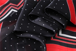 Detailed view of red and black polka dot silk scarf texture with geometric stripes