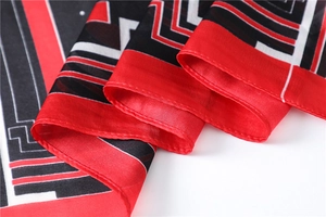 Detail of red, black and white geometric pattern on smooth silk scarf fabric texture