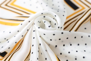 Detailed view of polka dot silk scarf featuring smooth texture and yellow stripe edges
